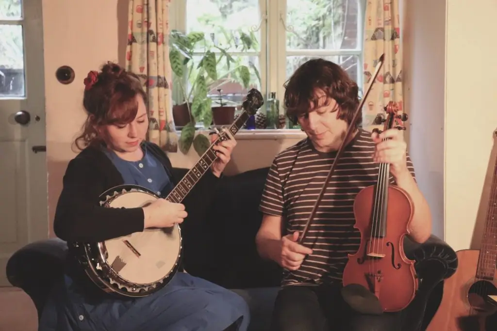 Christina Alden and Alex Patterson sitting and playing their musical instruments.